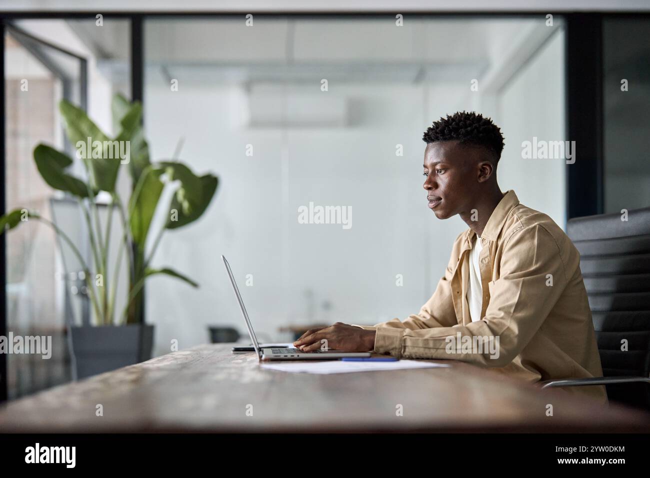 Beschäftigter, professioneller afrikanischer junger Geschäftsmann, der mit seinem Laptop am Schreibtisch arbeitet. Stockfoto