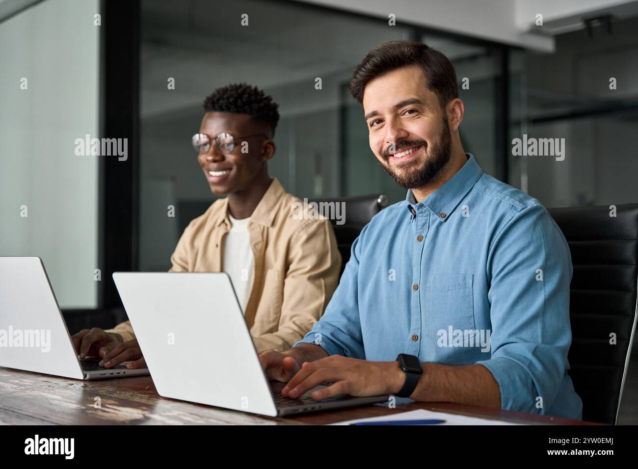Professioneller junger glücklicher Geschäftsmann, der mit einem Kollegen im Büro arbeitet, Porträt. Stockfoto