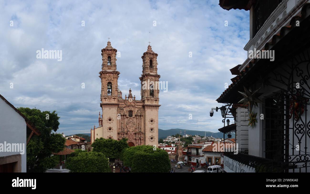 Ein bemerkenswerter Anblick der Kirche Santa Prisca in Taxco, Mexiko, mit ihrer komplexen barocken Architektur. Die Aussicht fängt üppiges Grün im ein Stockfoto