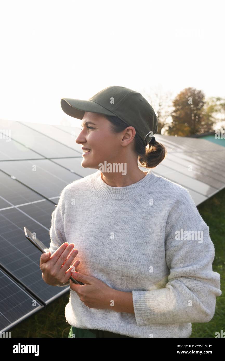 Farmerin mit digitalem Tablet auf einem modernen Bauernhof mit Solarpaneelen. Stockfoto