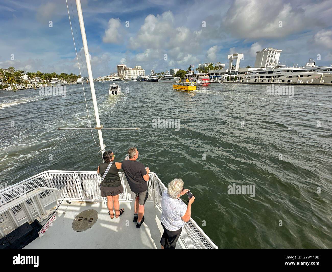 Fort Lauderdale, Florida, USA - 2. Dezember 2024: Menschen stehen auf dem vorderen Deck eines Touristenbootes, während es die Wasserstraße der Stadt hinauffährt Stockfoto