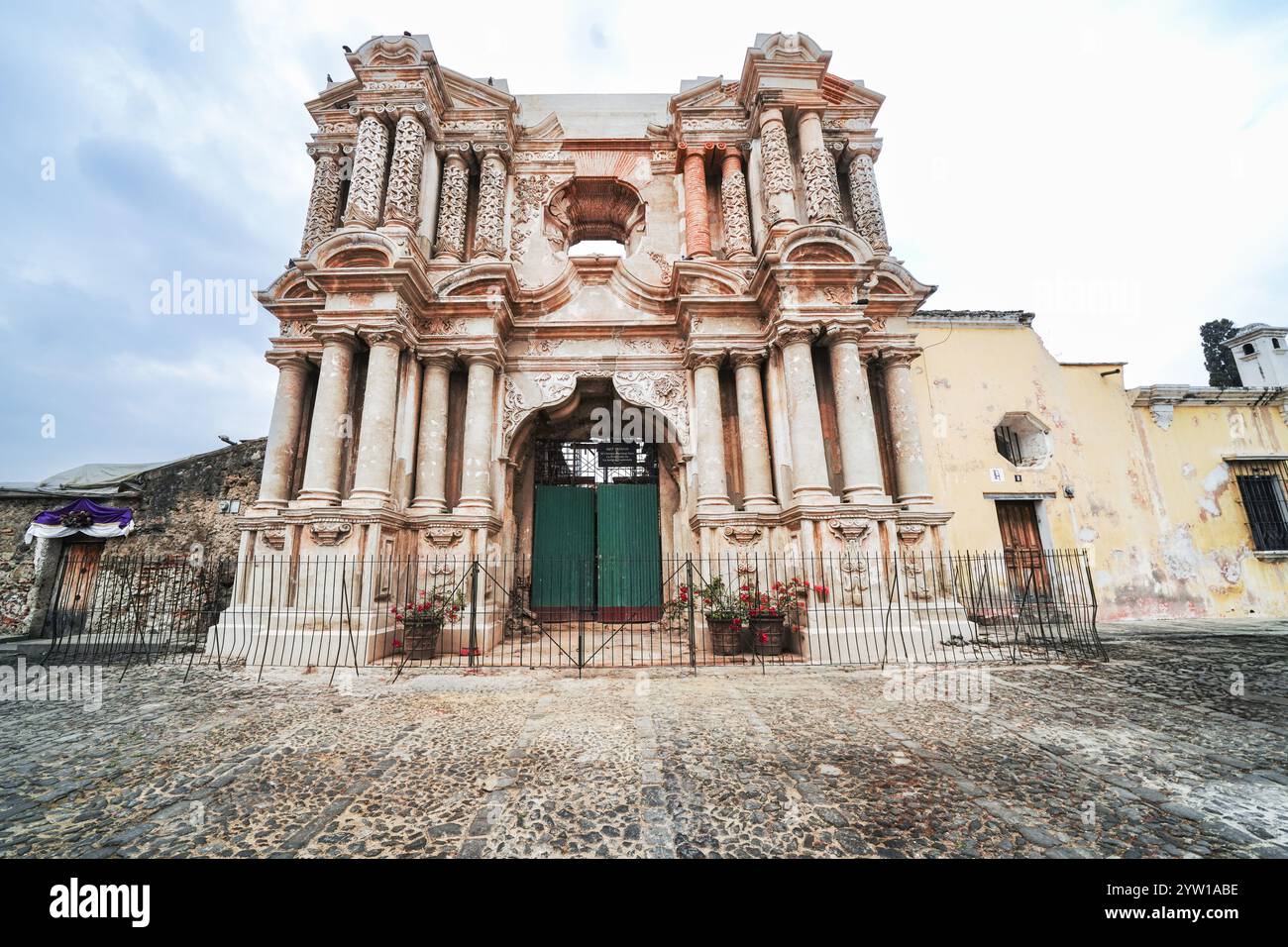 Außenfassade der Ruinen der Iglesia de Nuestra Señora de El Carmen oder der Kirche unserer Lieben Frau von Carmen, einer kunstvollen katholischen Kirche, die 1773 durch die Erdbeben in Santa Marta in Antigua, Guatemala, zerstört wurde. Vor den Ruinen findet oft ein wöchentlicher Kunsthandwerksmarkt statt. Stockfoto