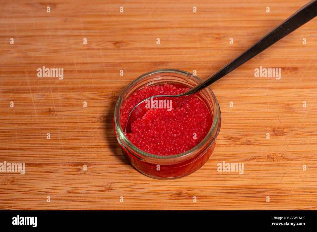 Roter Lumpish Reh und ein Löffel in einem Glas auf einem Schneidebrett Stockfoto