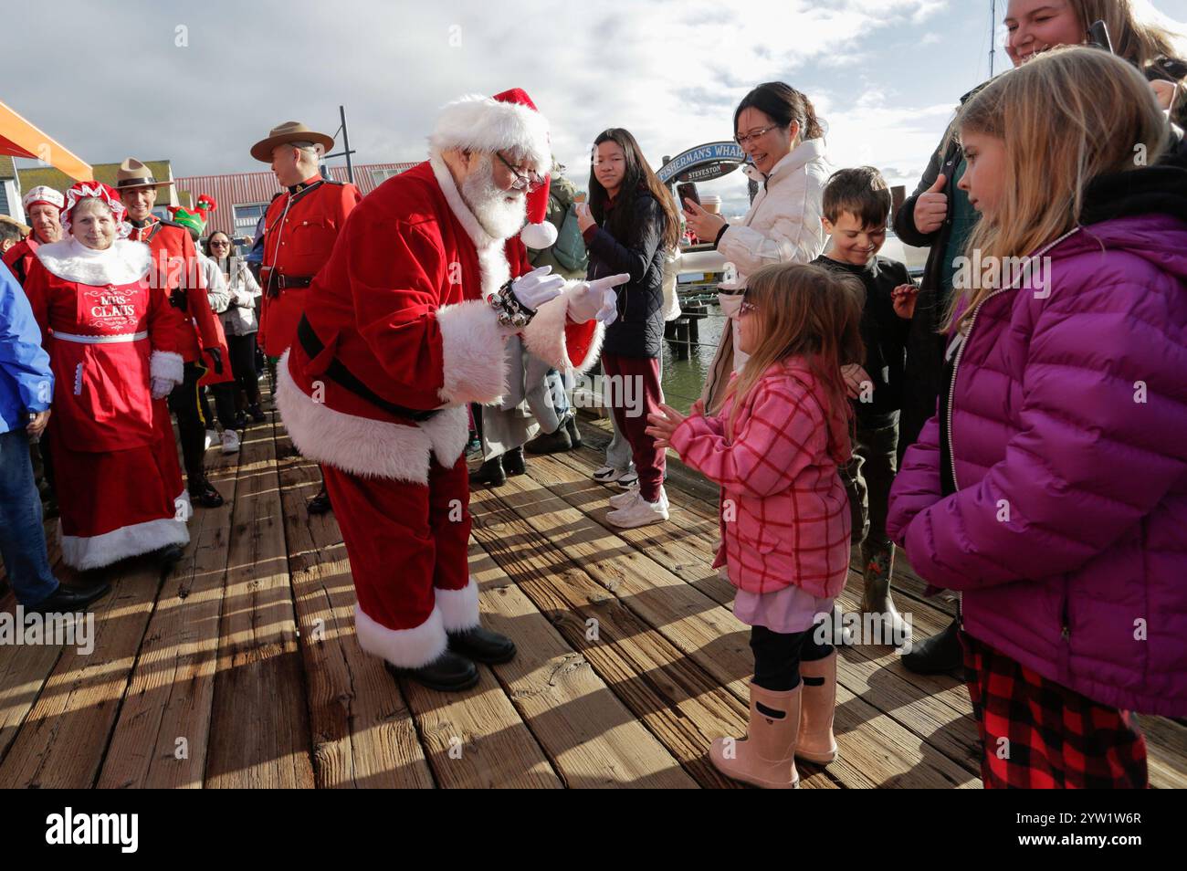 Richmond, Kanada. Dezember 2024. Ein als Weihnachtsmann gekleideter Mann interagiert am 8. Dezember 2024 mit einem Kind an der Steveston Fisherman's Wharf in Richmond, British Columbia, Kanada. Die Ankunft des Weihnachtsmanns mit dem Boot fand hier am Sonntag statt, um die Weihnachtszeit zu beginnen. Quelle: Liang Sen/Xinhua/Alamy Live News Stockfoto