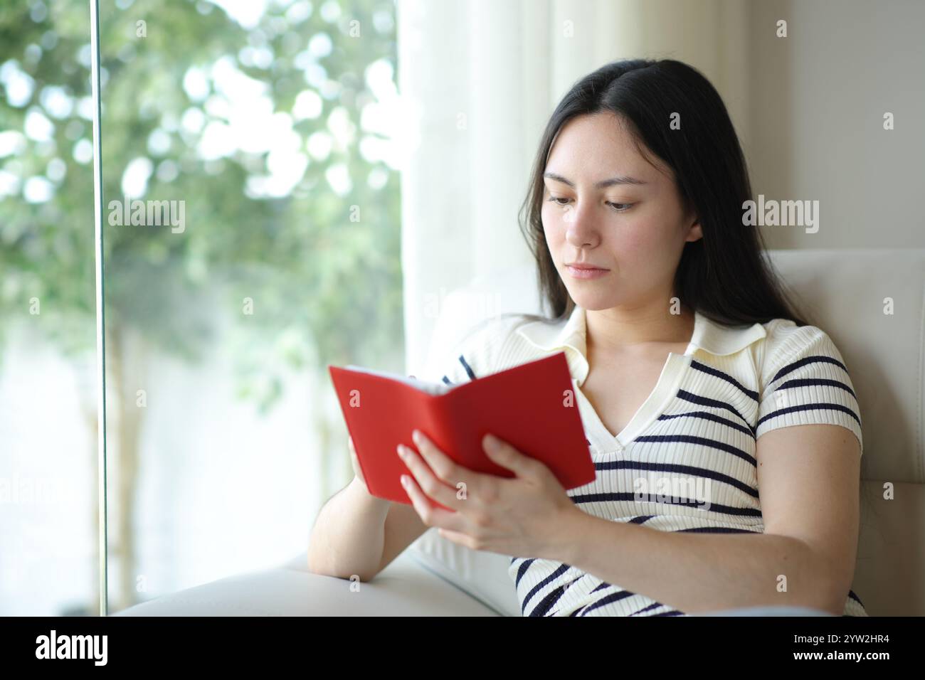 Ernsthafte asiatische Frau, die zu Hause Notizen auf der Tagesordnung macht Stockfoto