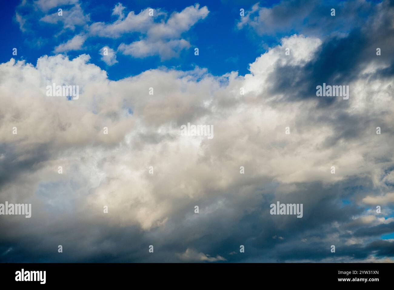 Bewölkter Himmel mit verschiedenen Schattierungen von weißen und grauen Wolken vor blauem Hintergrund. Stockfoto