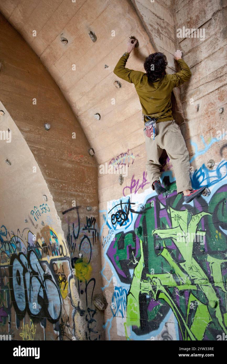Junge Kletterer Bouldern unter einer urbanen Brücke umgeben von Graffiti. Stockfoto