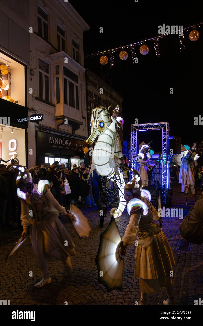 AALST, BELGIEN, 6. DEZEMBER 2024: Leuchtende Figuren unterhalten Menschenmassen auf der Einkaufsstraße beim Weihnachtsfest von Aalst Twinkles. Am Abend Stockfoto