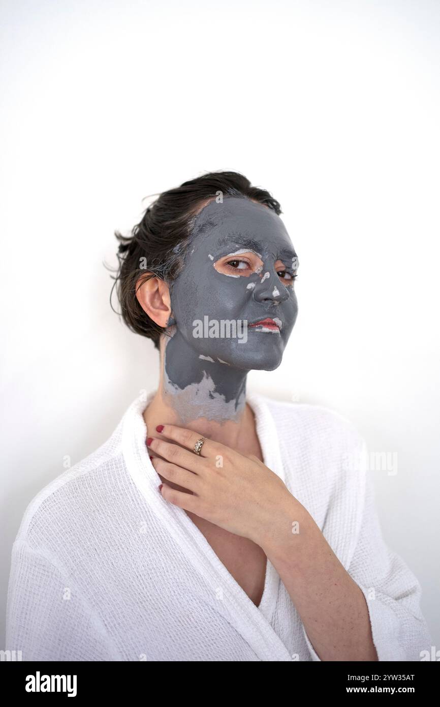 Junge Frau mit einer Gesichtsmaske, die vor weißem Hintergrund posiert. Stockfoto