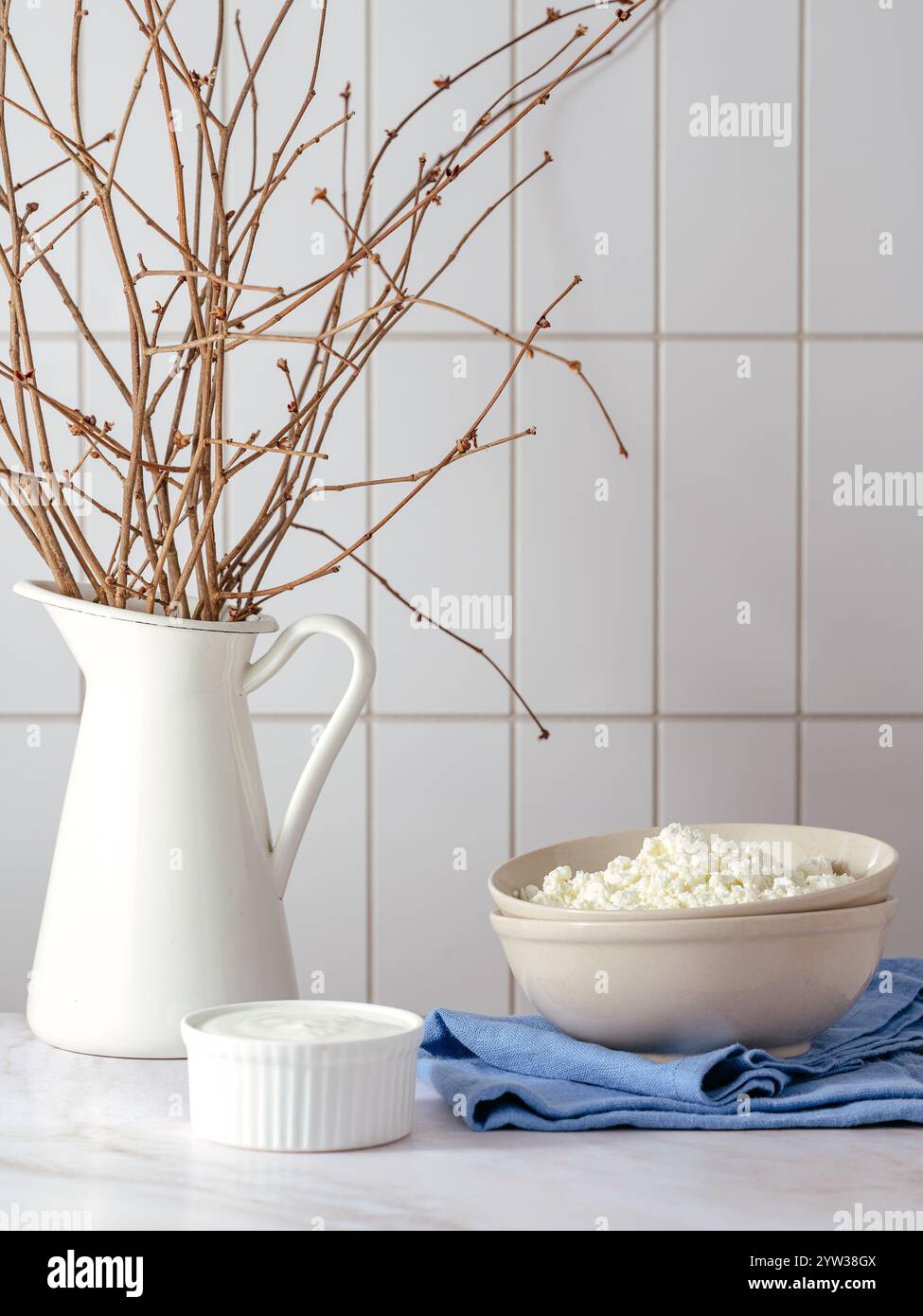Hüttenkäse in einer Schüssel auf dem Hintergrund einer hellen Küche Stockfoto