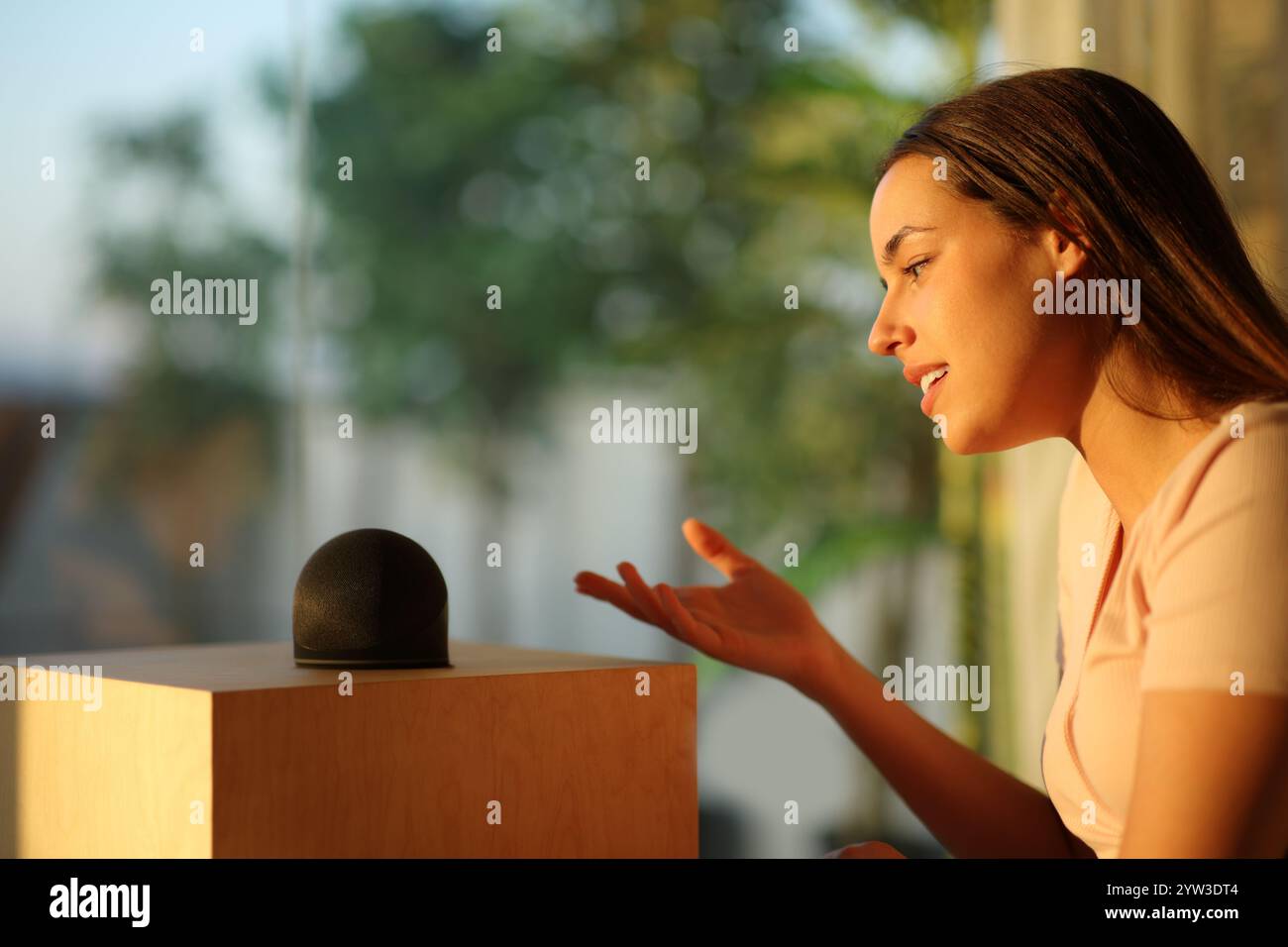 Profil einer Frau, die mit Smart Speaker im Susnet zu Hause spricht Stockfoto