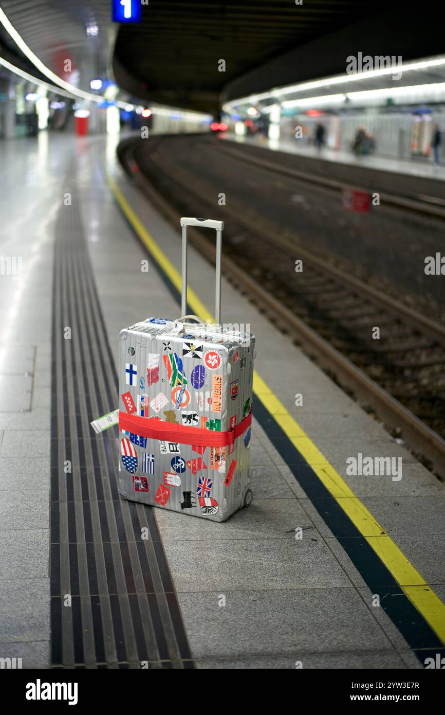 Ein mit Reiseaufklebern bedeckter Koffer auf einem verlassenen Bahnsteig in Wien, Österreich Stockfoto