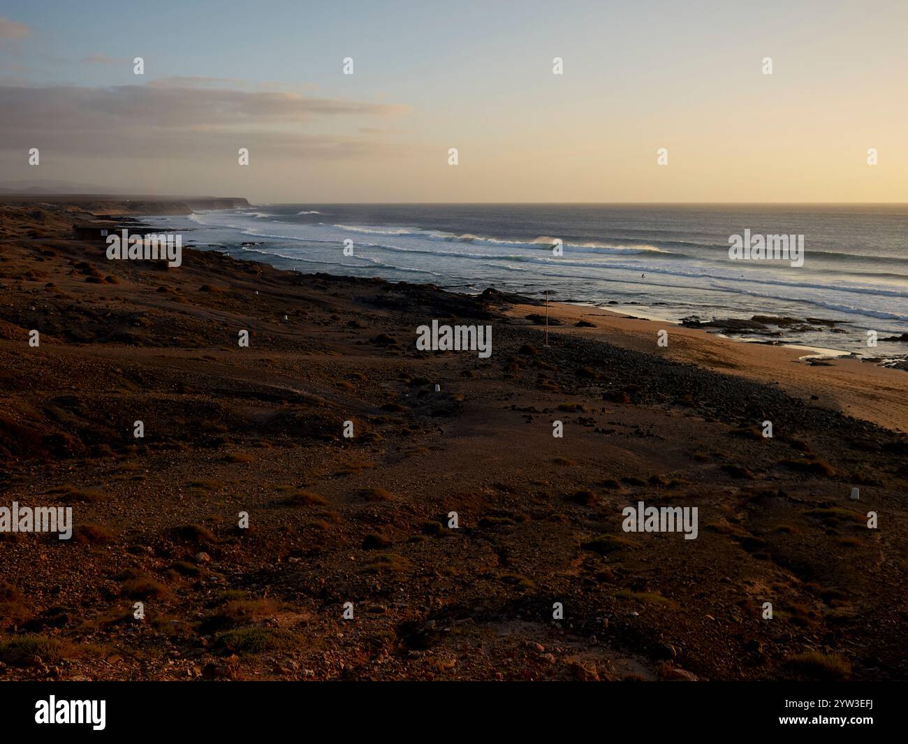 Sonnenuntergang über einem ruhigen Strand mit sanften Wellen, der den Kontrast zwischen dem Sandstrand und dem weiten Meer, Fuerteventura, Spanien, unterstreicht Stockfoto