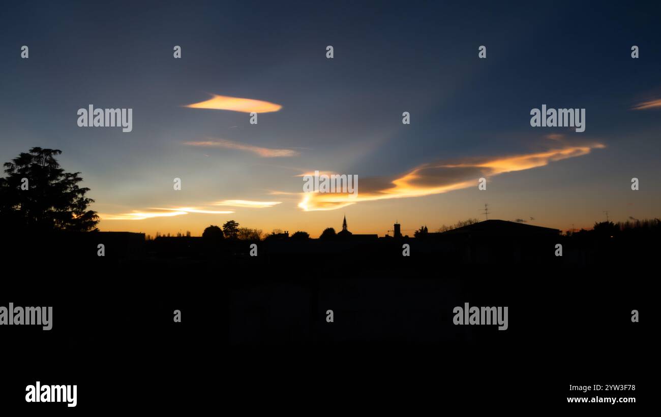 Schillernde Wolken während eines wunderschönen Wintersonnenverkehrs über der Stadt. Stockfoto