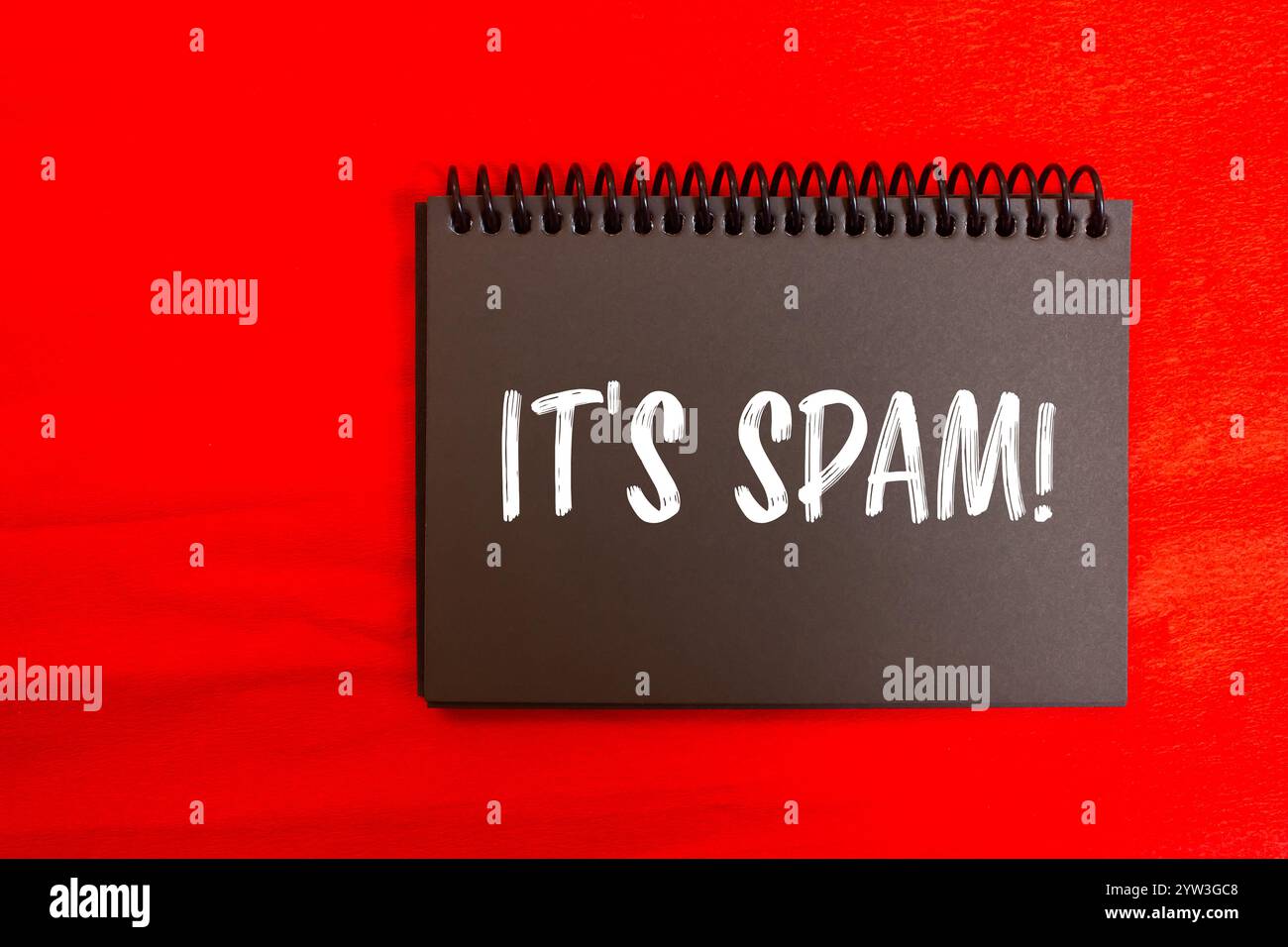 Es ist eine Spam-Nachricht auf schwarzer Notizbuchseite mit rotem Hintergrund. Konzeptionell ist das Spam-Symbol. Kopierbereich. Stockfoto