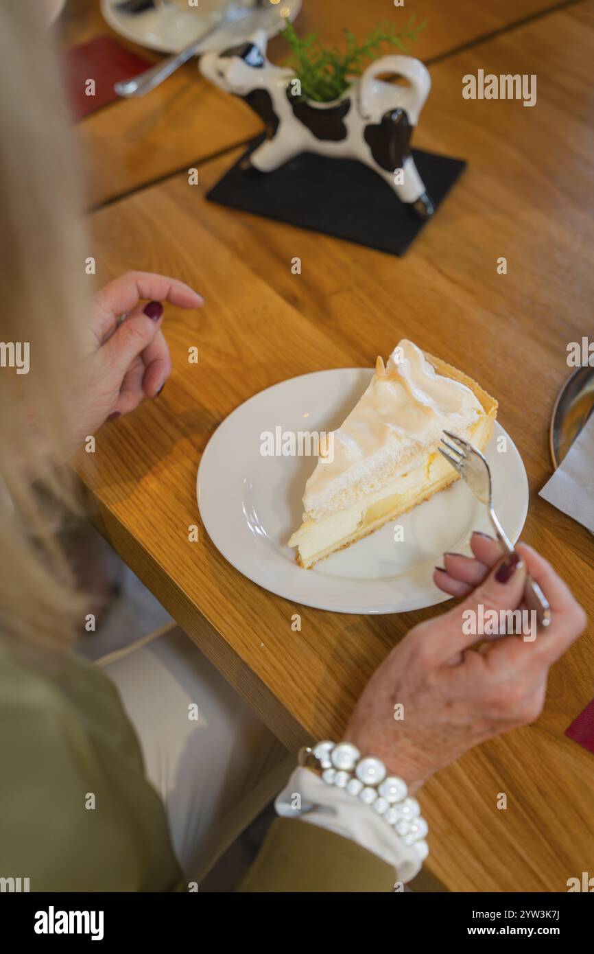 Frau genießt ein Stück Zitronenkuchen mit Meringue in einem Café, Herbstkreationen, Cafe Kuh, Deckenpfronn, Schwarzwald, Deutschland, Europa Stockfoto