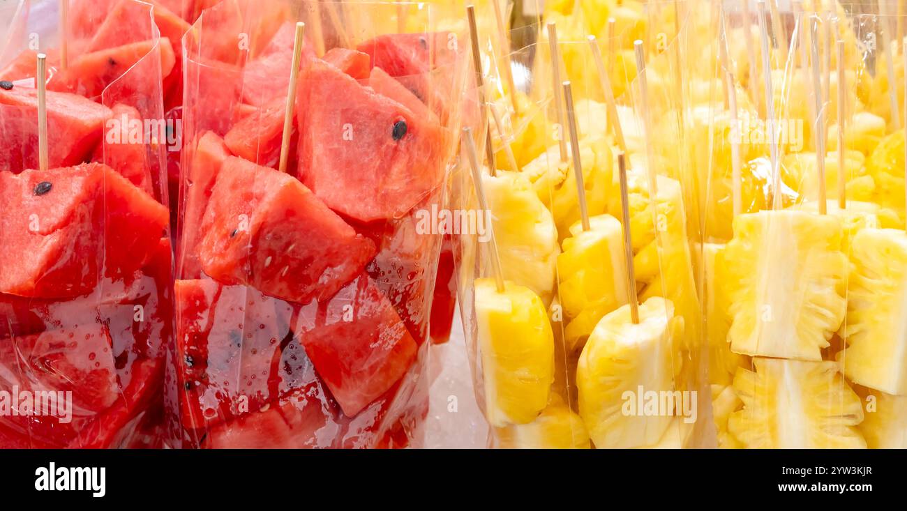 Der ganze Rahmen aus roter Wassermelone und gelber Ananas in Stücken oder Scheiben in transparenter Plastiktüte ist am Street Food Stand erhältlich. Stockfoto