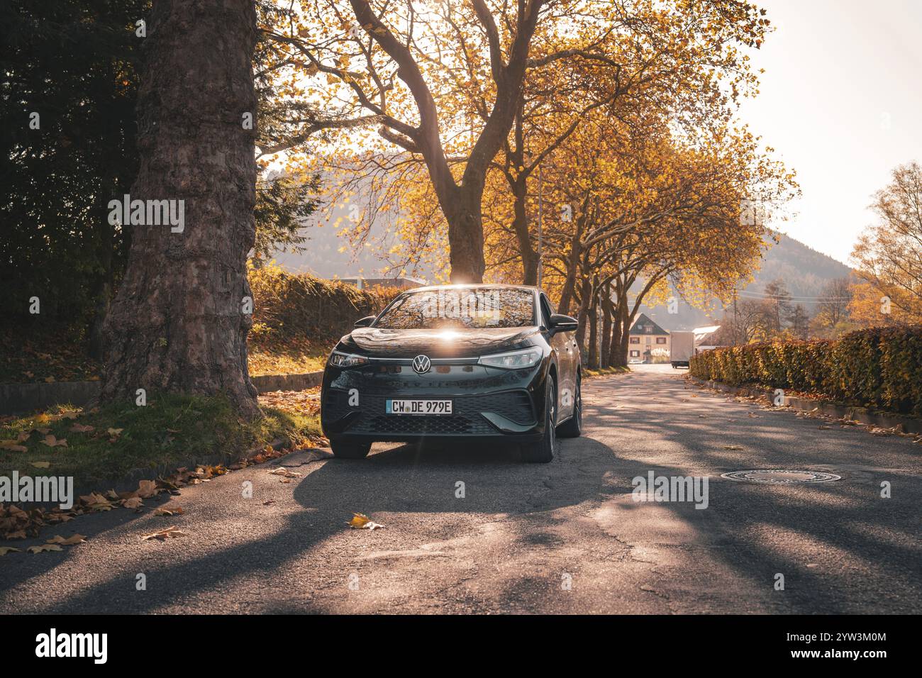 Auto im Sonnenlicht auf einer Herbstallee, Elektroauto VW ID5, Deer Carsharing, Gechingen, Schwarzwald, Deutschland, Europa Stockfoto