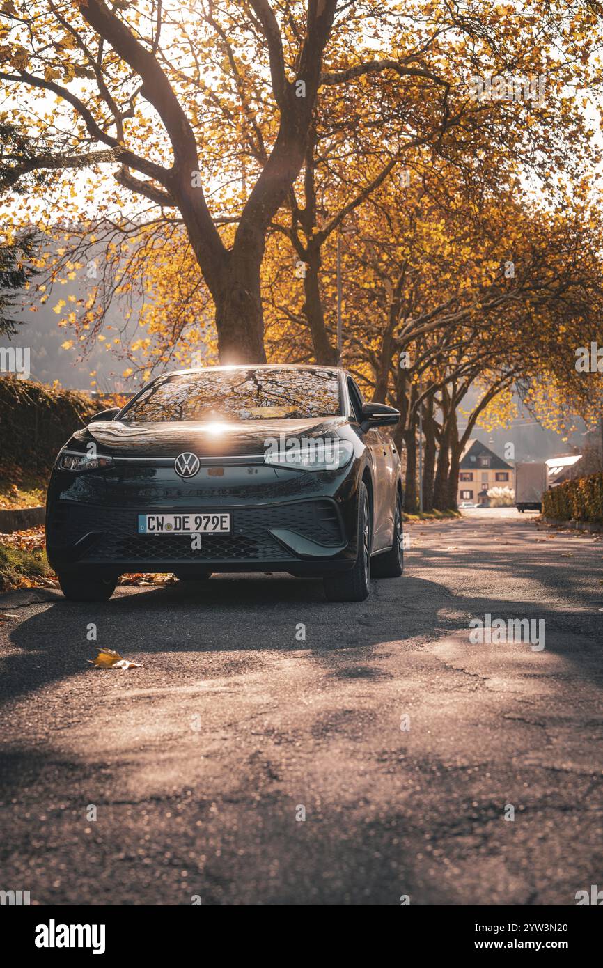 Auto im Schatten auf einer Herbstallee mit Sonnenlicht, Elektroauto VW ID5, Hirschcarsharing, Gechingen, Schwarzwald, Deutschland, Europa Stockfoto