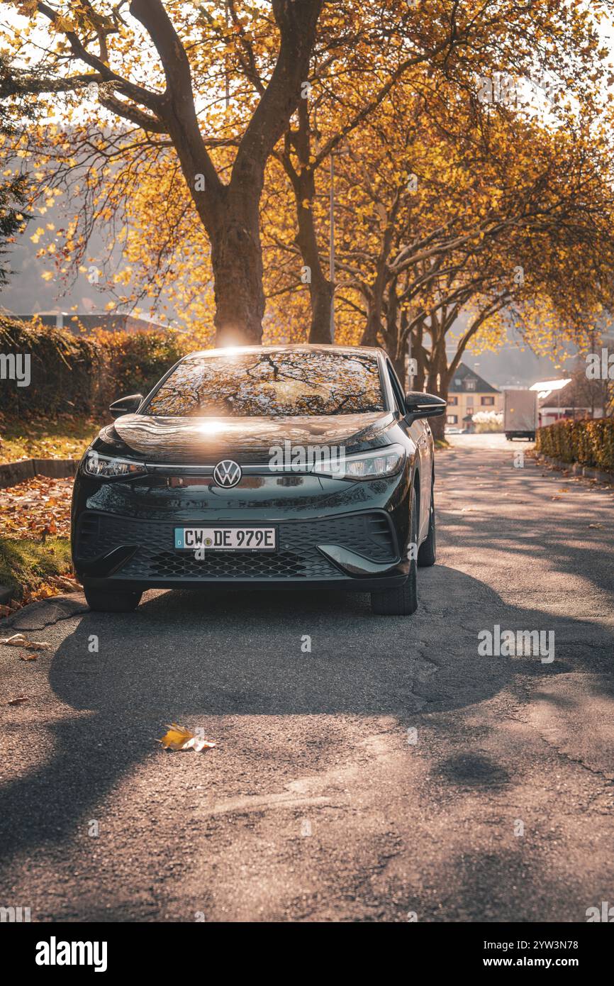 Auto im Sonnenlicht auf einer von Bäumen gesäumten Straße, Elektroauto VW ID5, Deer Carsharing, Gechingen, Schwarzwald, Deutschland, Europa Stockfoto