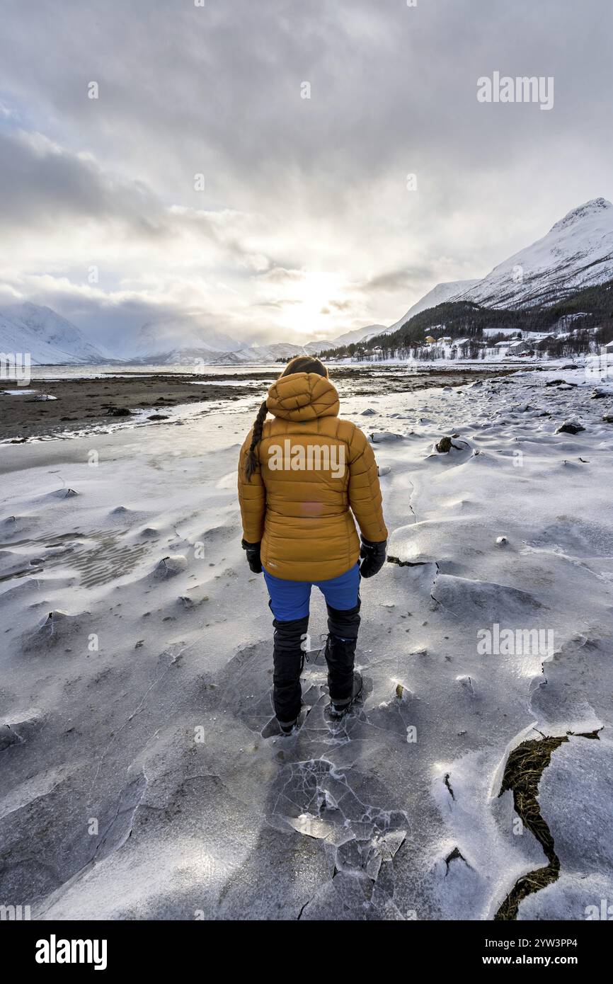 Eine Frau in Winterkleidung am gefrorenen Ufer des Ullsfjords, Sjursnes, Tromso, Troms, Norwegen, Europa Stockfoto