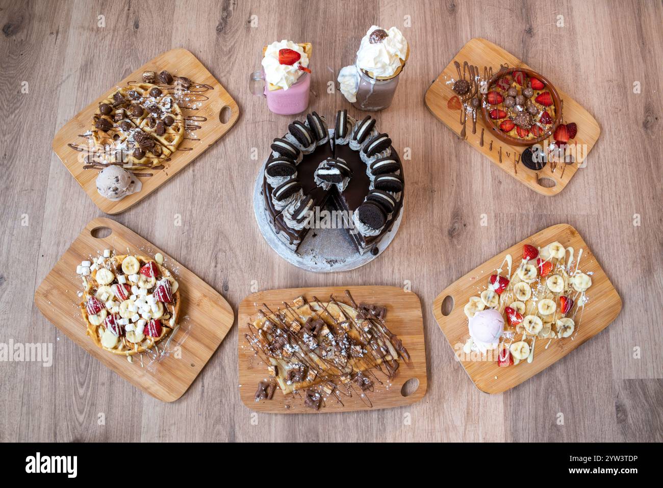 Ausgewählte Desserts, darunter Erdbeeren- und Bananenkrepé, Keksteig, Schokoladenwaffeln und Milchshakes Stockfoto