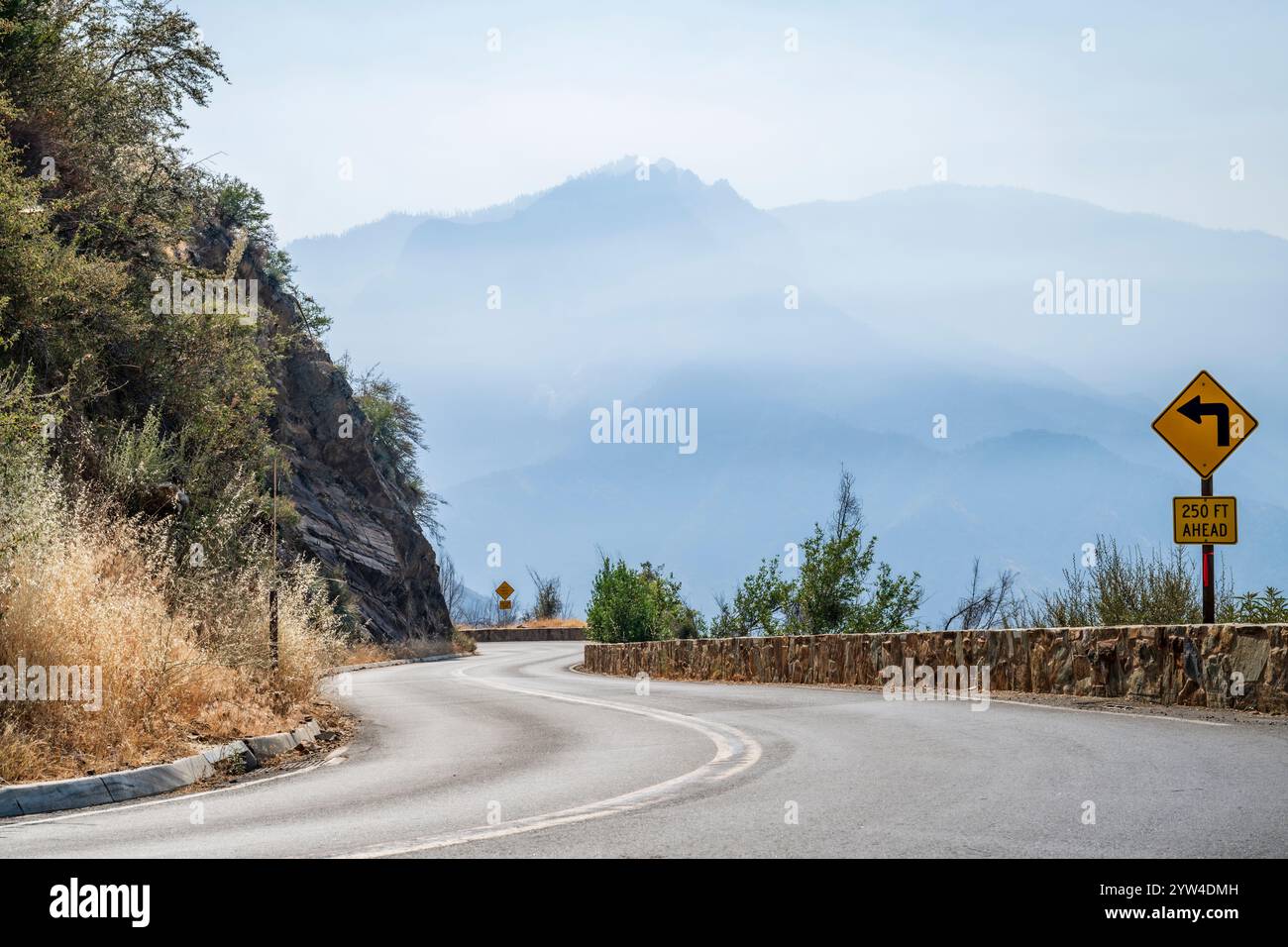 Gekrümmte, leere Straße, die an sonnigen Sommertagen durch die Berglandschaft der Sierra Nevada führt, Sequioa National Park, Kalifornien, USA Stockfoto