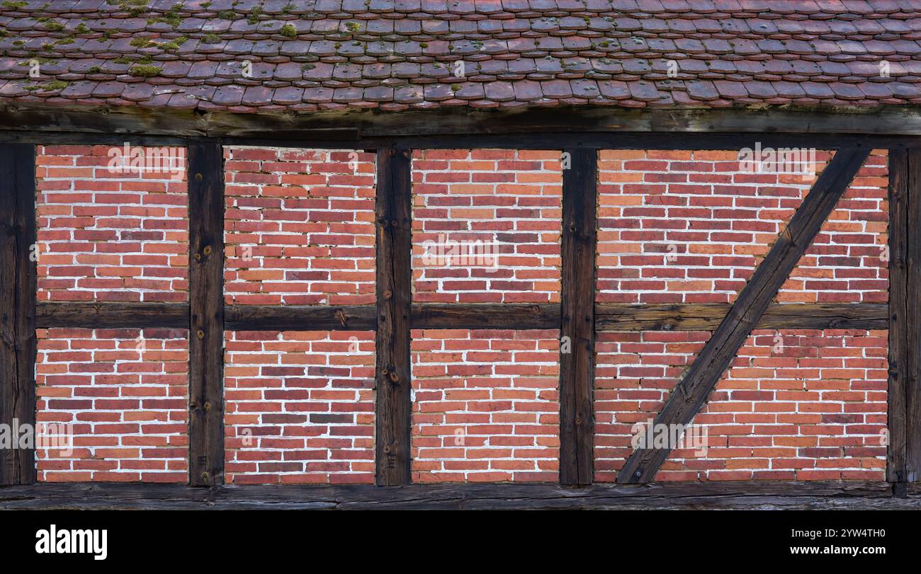 Alte Fassade aus Fachwerk mit Ziegelsteinen, über einem Teil des Daches Stockfoto