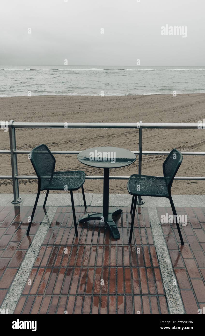 Nasse Tische und Stühle am Strand an einem regnerischen Tag Stockfoto