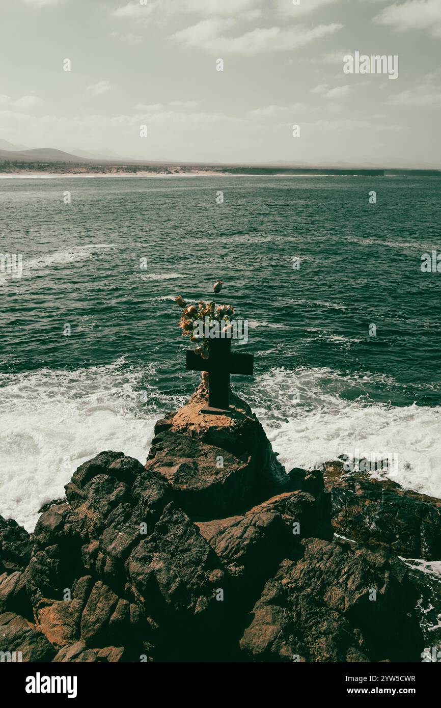 Blumen und Kreuz auf Felsen, Klippe mit Blick auf Meer und Meer Stockfoto