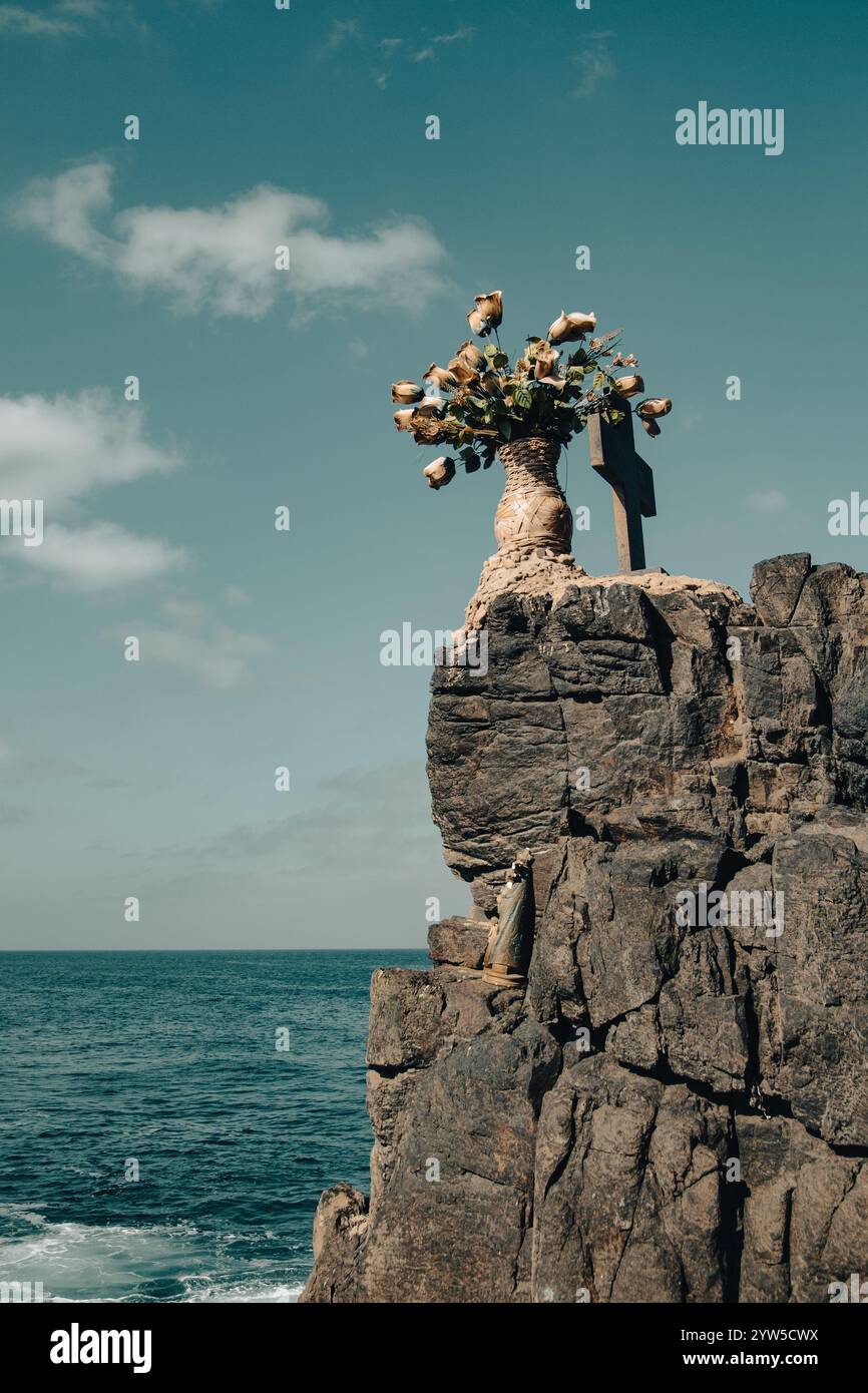 Blumen und Kreuz auf Felsen, Klippe mit Blick auf Meer und Meer Stockfoto