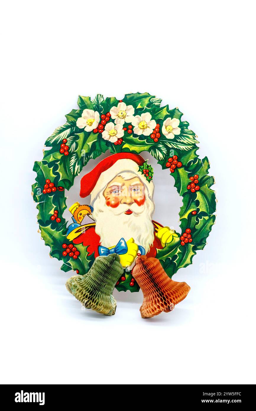 Vintage Weihnachtsmann hängende Weihnachtsdekoration in einem traditionellen roten Anzug mit weißem Pelzbesatz und Krepppapier-Glocken Stockfoto