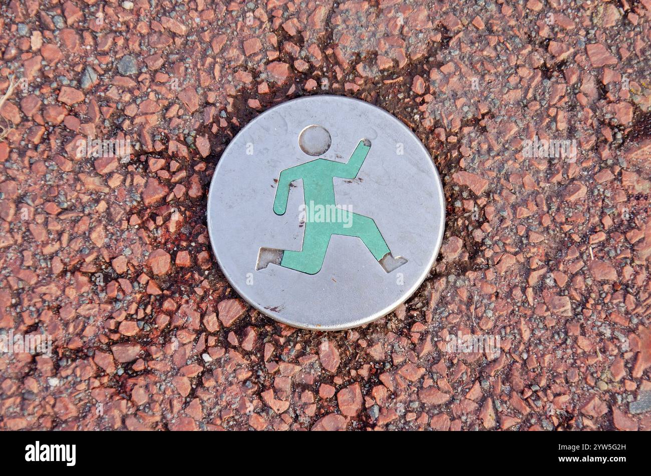 Amsterdam, Niederlande, 24. November 2024: Symbol mit Laufperson in rotem Asphalt, die eine empfohlene ununterbrochene Laufstrecke anzeigt Stockfoto