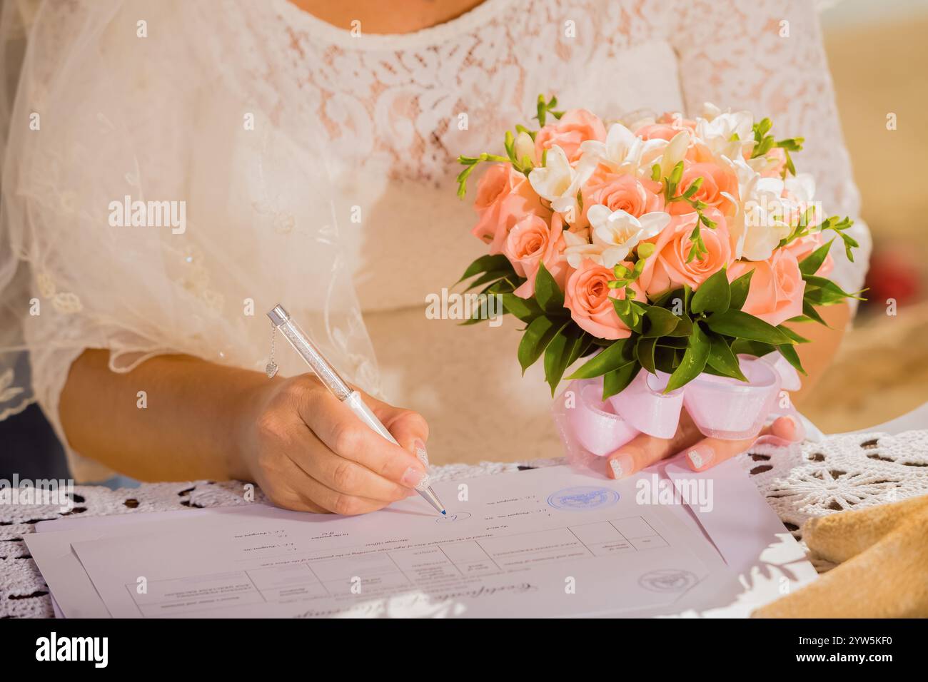 Die Braut unterschreibt die Hochzeitsurkunde während der Trauung, Bescheinigung über die Registrierung der Heiratsurkunde. Braut unterschreibt die Hochzeit regi Stockfoto