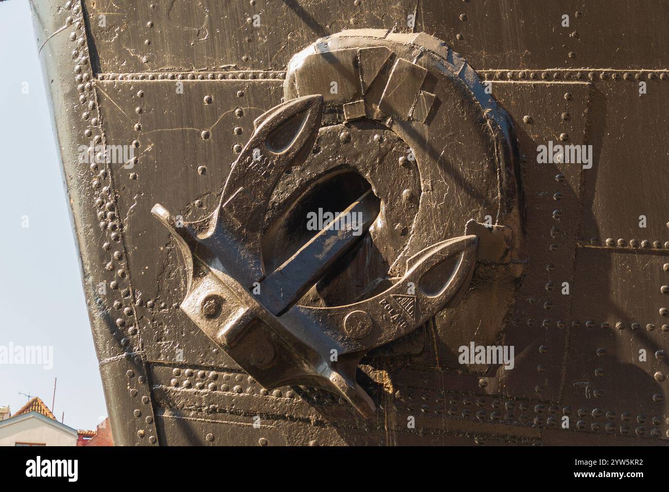 Nahaufnahme eines Schiffsbogens mit montiertem Anker und vernietetem, dunkel lackiertem Metallrumpf. Stockfoto