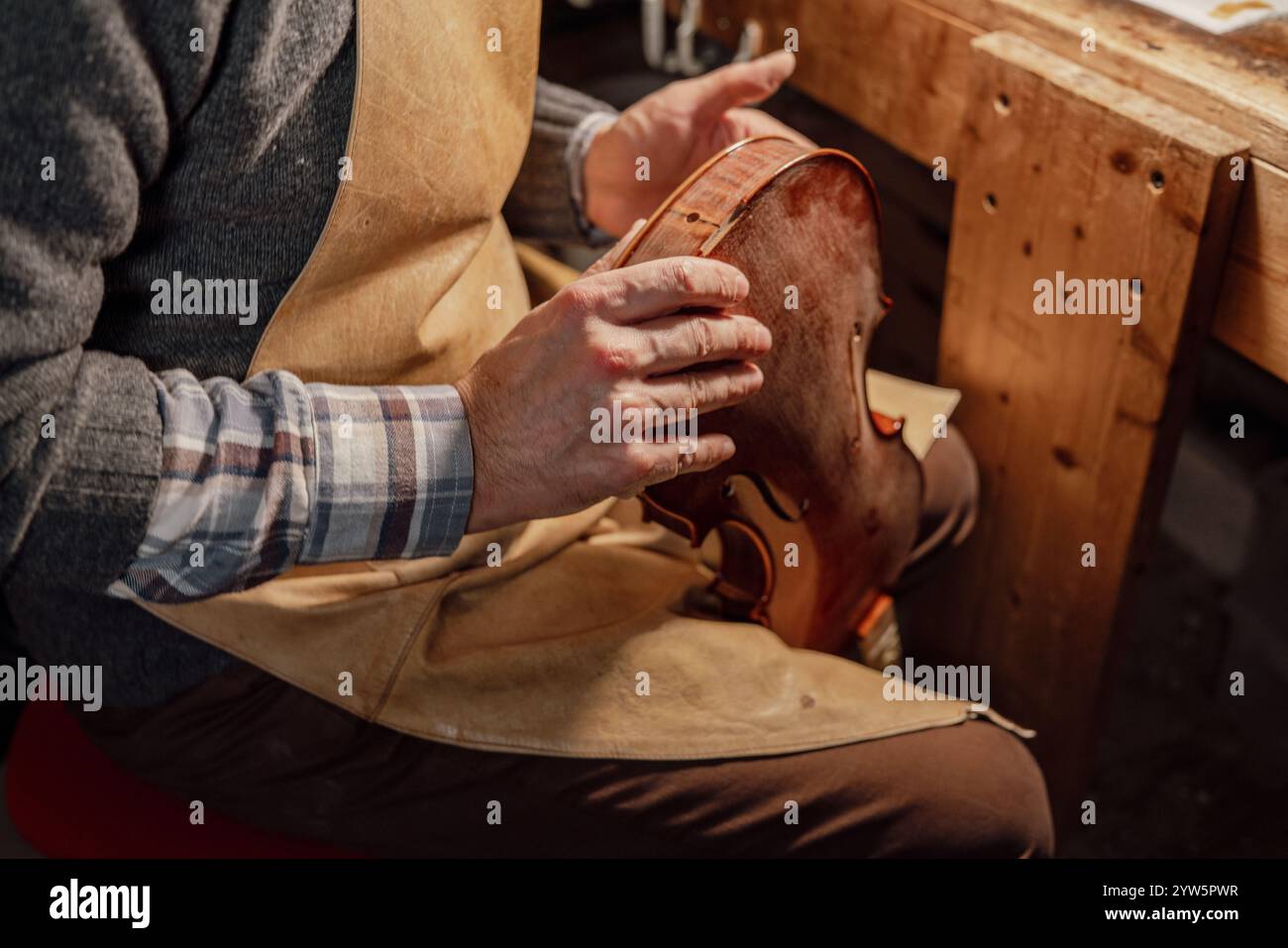 Geigenbauer überprüft die Oberflächen einer handgefertigten Geige in seiner Werkstatt Stockfoto