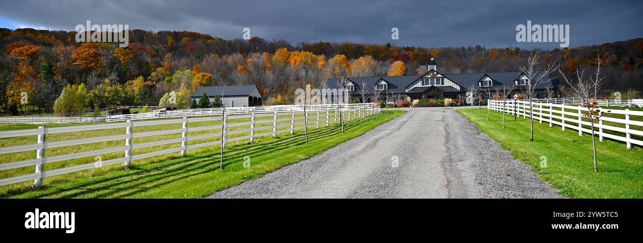 Webbanner - schwindender perspektivischer Blick auf einen Pferdestall mit weißen Zäunen in Herbstfarbe Stockfoto