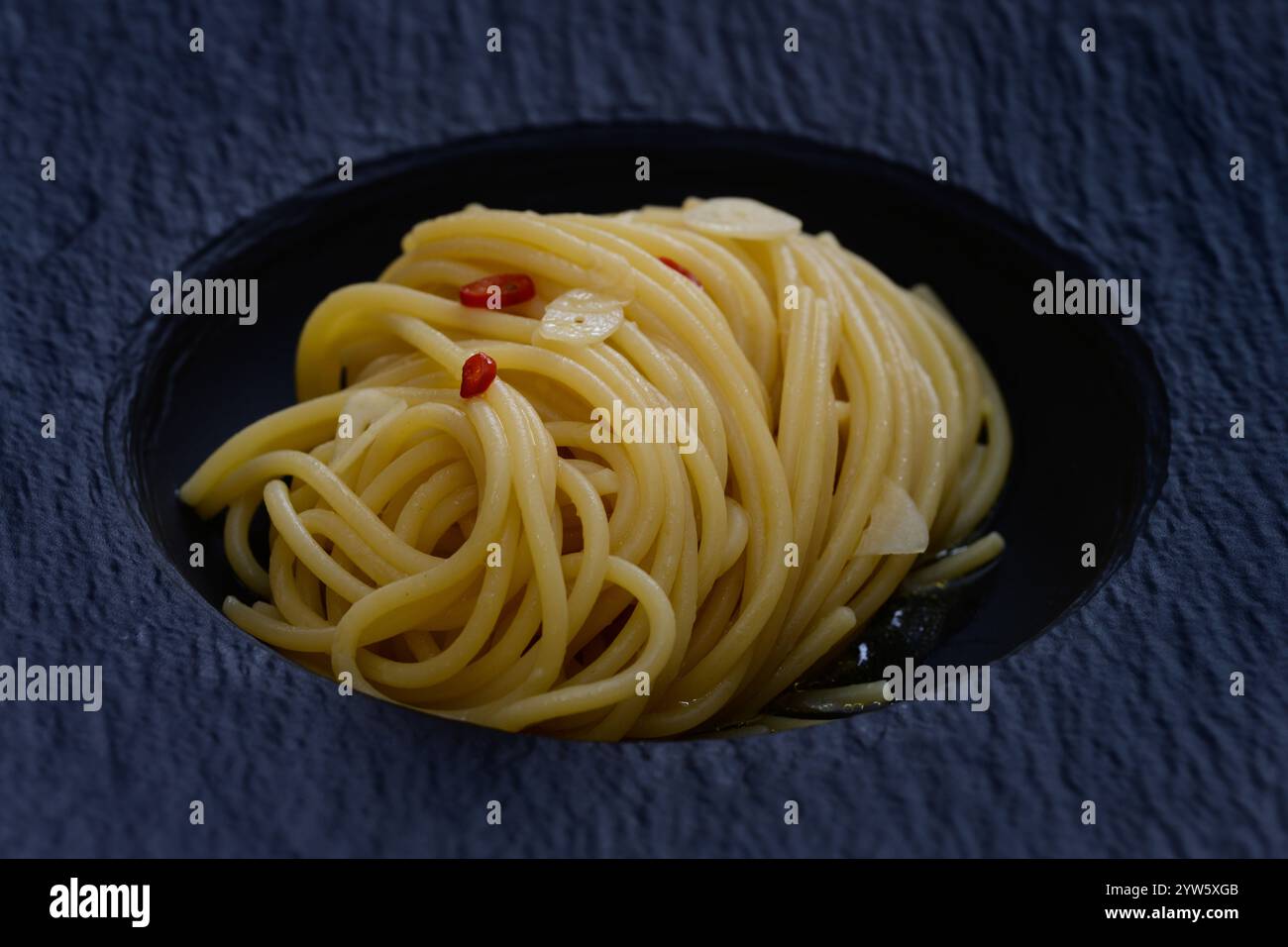 Spaghetti Colatura di Alici mit Knoblauch und Peperoncini auf einer schwarzen Platte Nahaufnahme Stockfoto