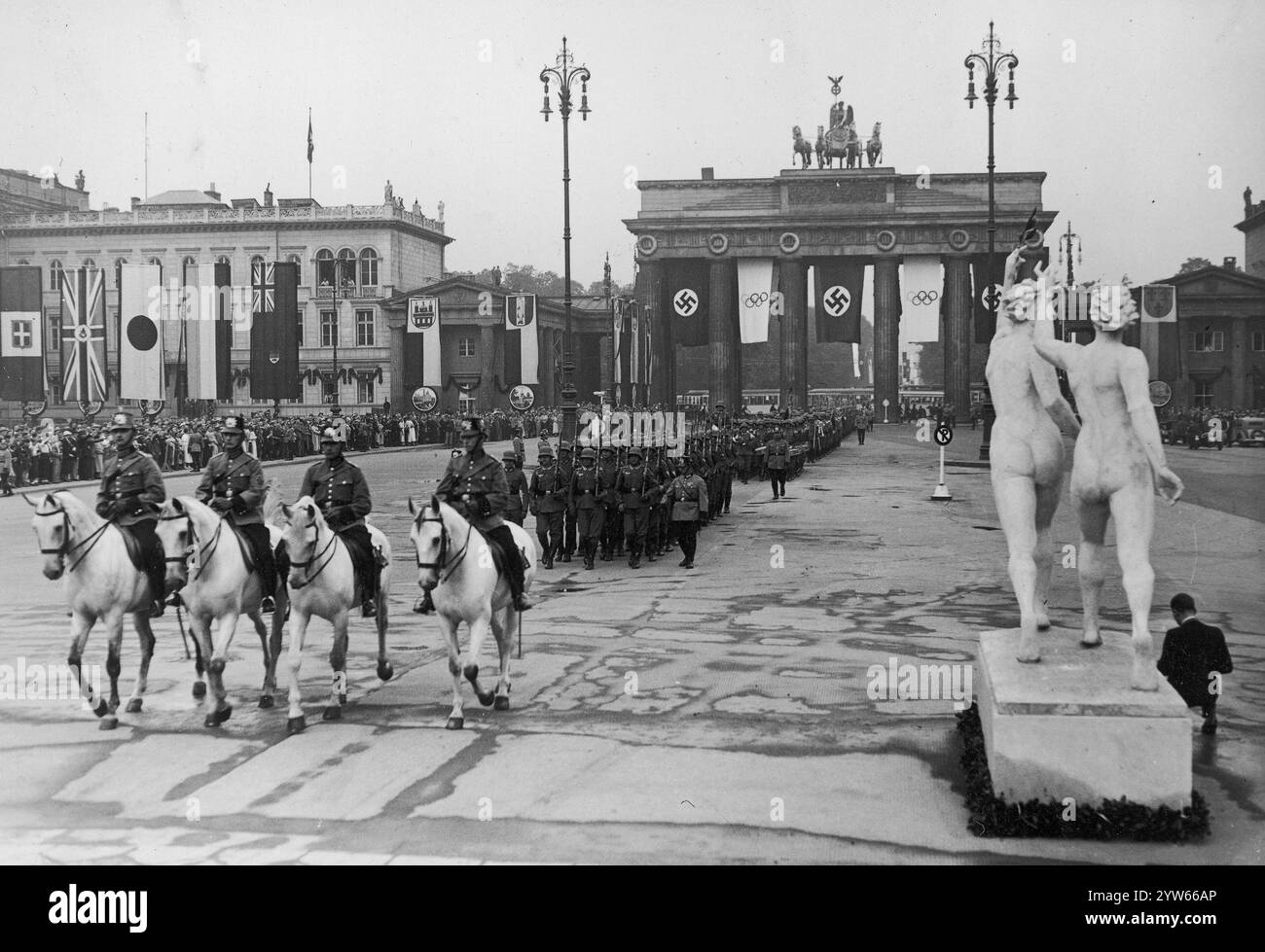 Eröffnung der Olympischen Spiele in Berlin. Marsch der Truppen des Dritten Reiches durch das Brandenburger Tor. Sichtbare Menschenmassen beobachten das Spektakel. Darüber befinden sich die Flaggen der Länder, die an den Olympischen Spielen teilnehmen. Archivfoto der Olympischen Sommerspiele 1936 in Berlin Stockfoto