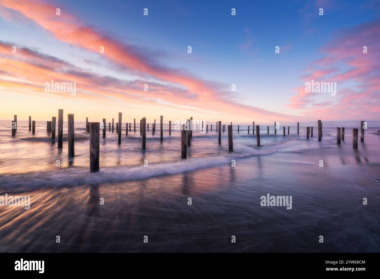 Ruhiger Sonnenuntergang über hölzernen Polen am Petten Beach, Niederlande Stockfoto