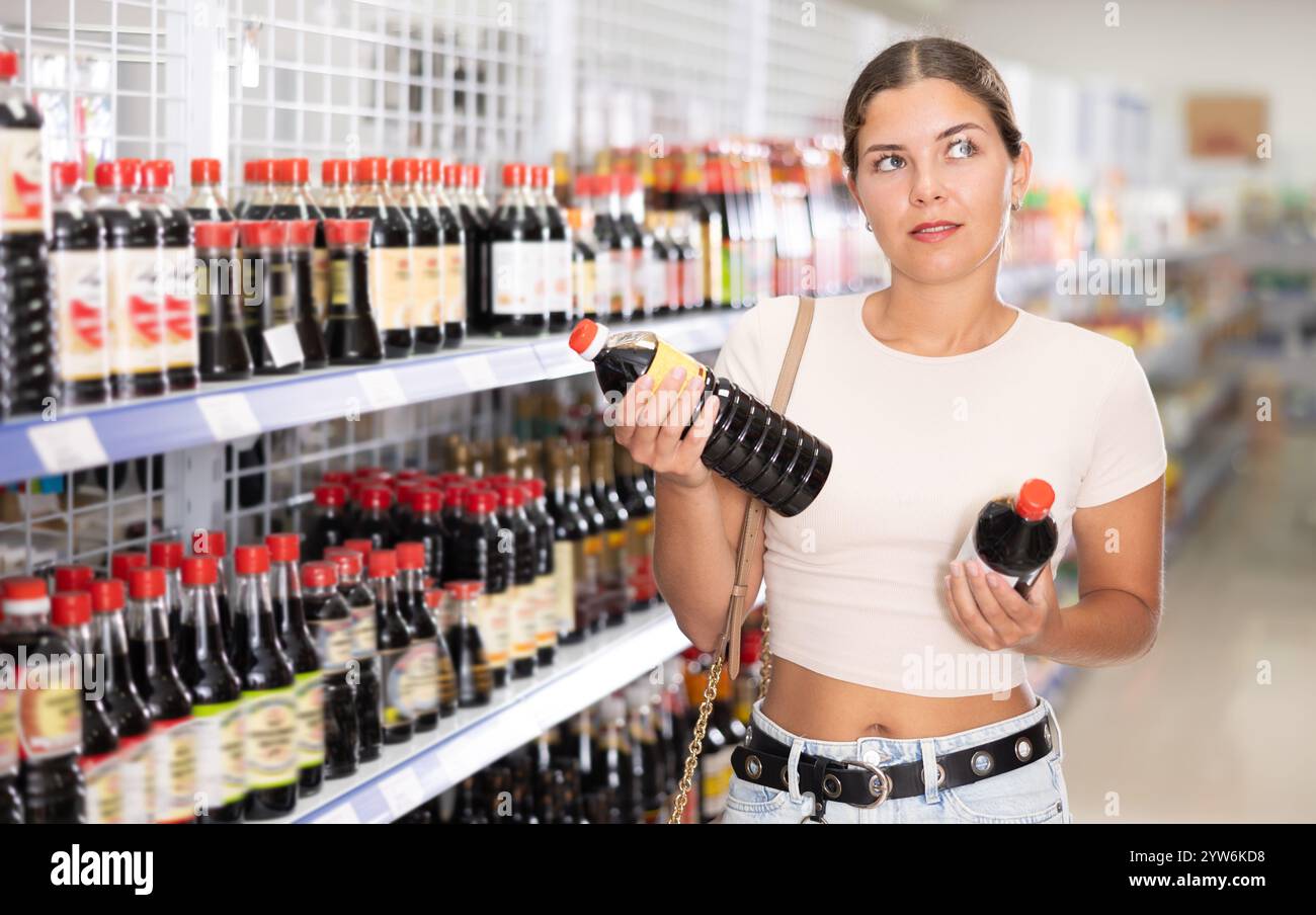 Ein junges Mädchen, das eine Flasche Sojasauce in einem asiatischen Lebensmittelgeschäft auswählt Stockfoto