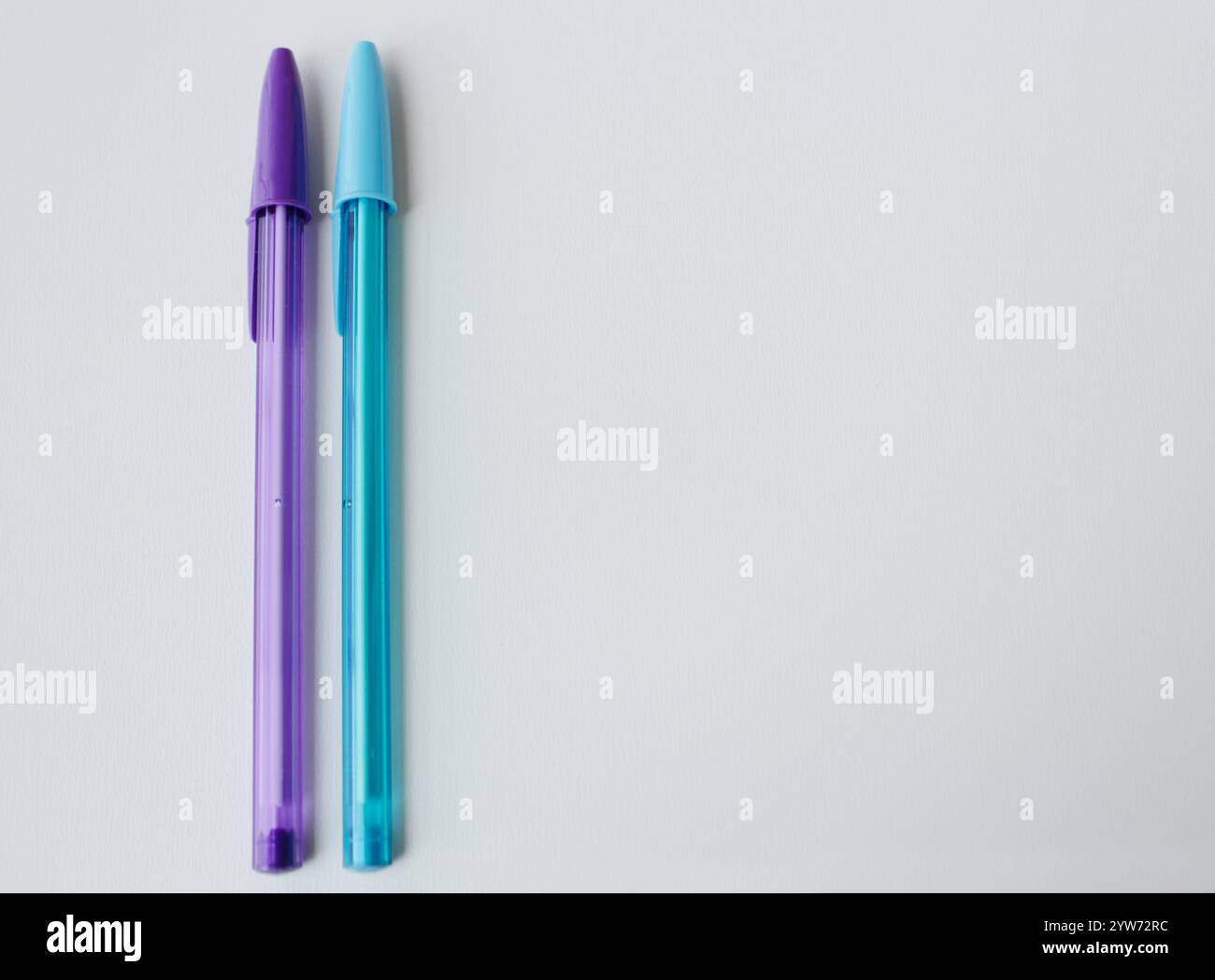 Zwei Kugelschreiber in coolen Farben nebeneinander, Hintergrund mit Kopierraum. Blauer und lila Stift. Kreative Schreibwaren, Schulbedarf, Handschriftenunterricht. Stockfoto