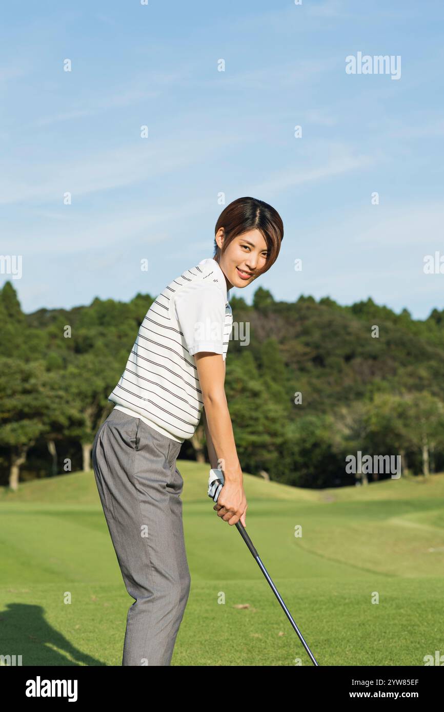 Eine Frau in ihren 20s, die Golf spielt Stockfoto