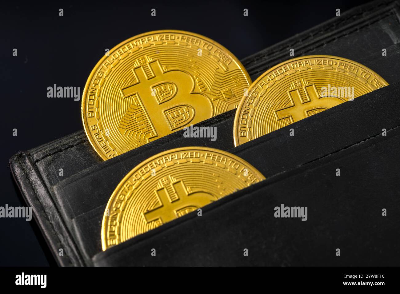 Goldene Bitcoin-Münzen, sichtbar in einer offenen schwarzen Ledertasche Stockfoto