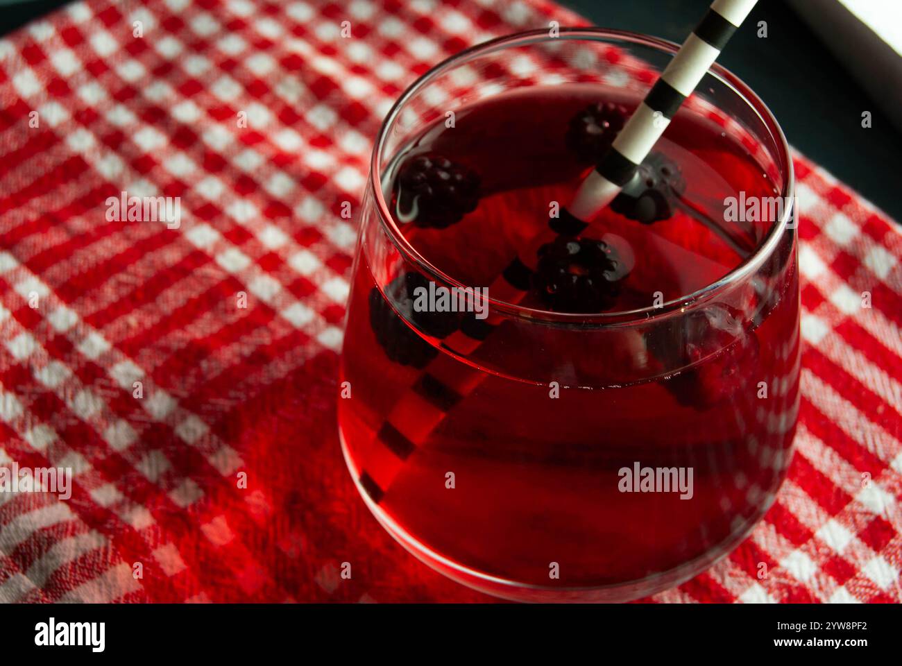 Erfrischender Himbeersaft in einem transparenten Glas mit einem lustigen Papierstroh. Stockfoto