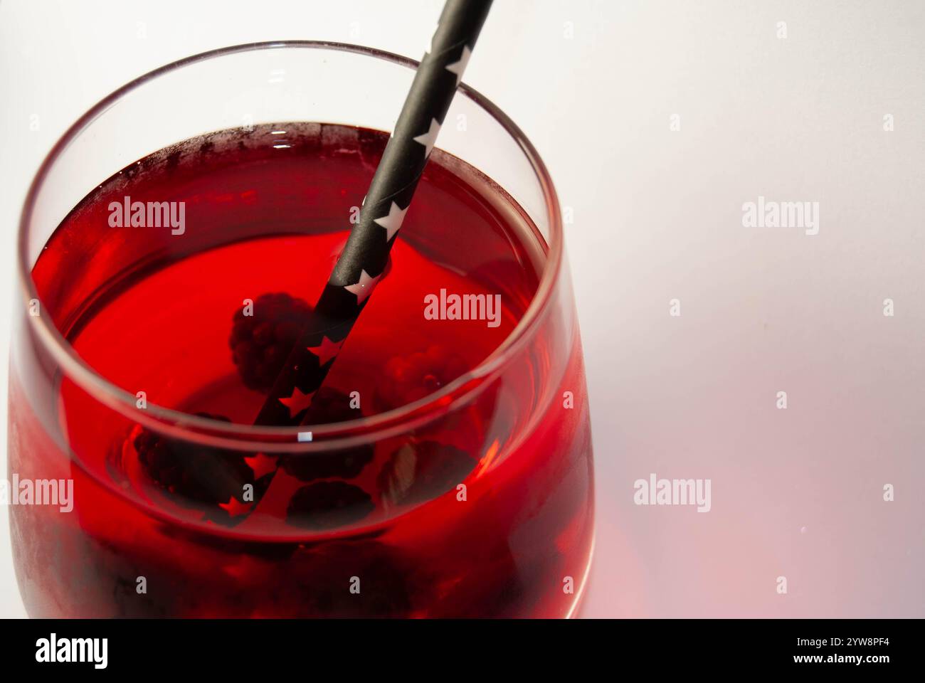 Erfrischender Himbeersaft in einem transparenten Glas mit einem lustigen Papierstroh. Stockfoto