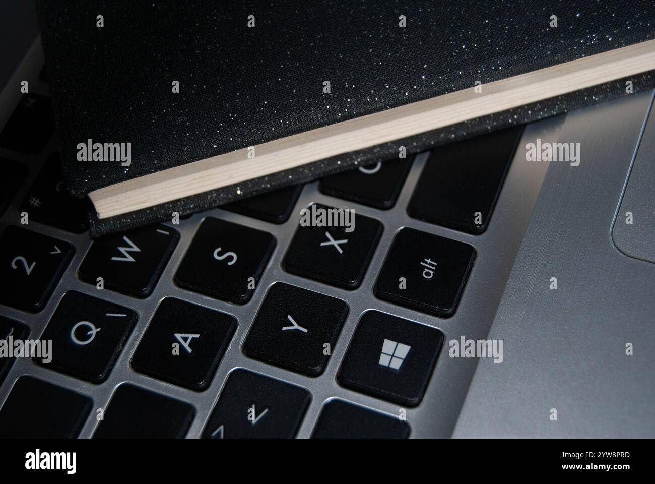 Ein elegantes, glänzendes schwarzes Notebook auf einer Notebook-Tastatur, das moderne Produktivität und Stil symbolisiert. Stockfoto