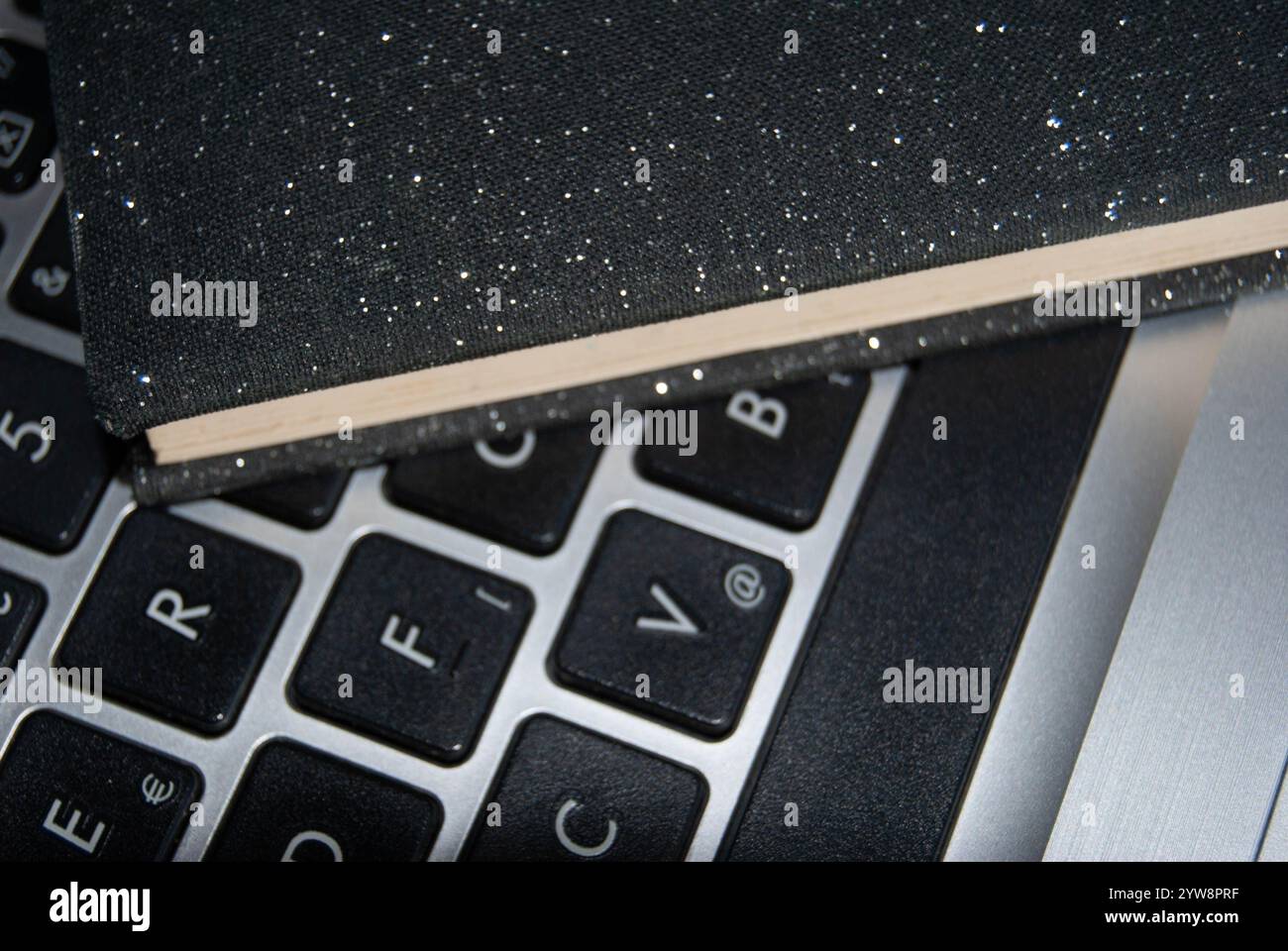 Ein elegantes, glänzendes schwarzes Notebook auf einer Notebook-Tastatur, das moderne Produktivität und Stil symbolisiert. Stockfoto