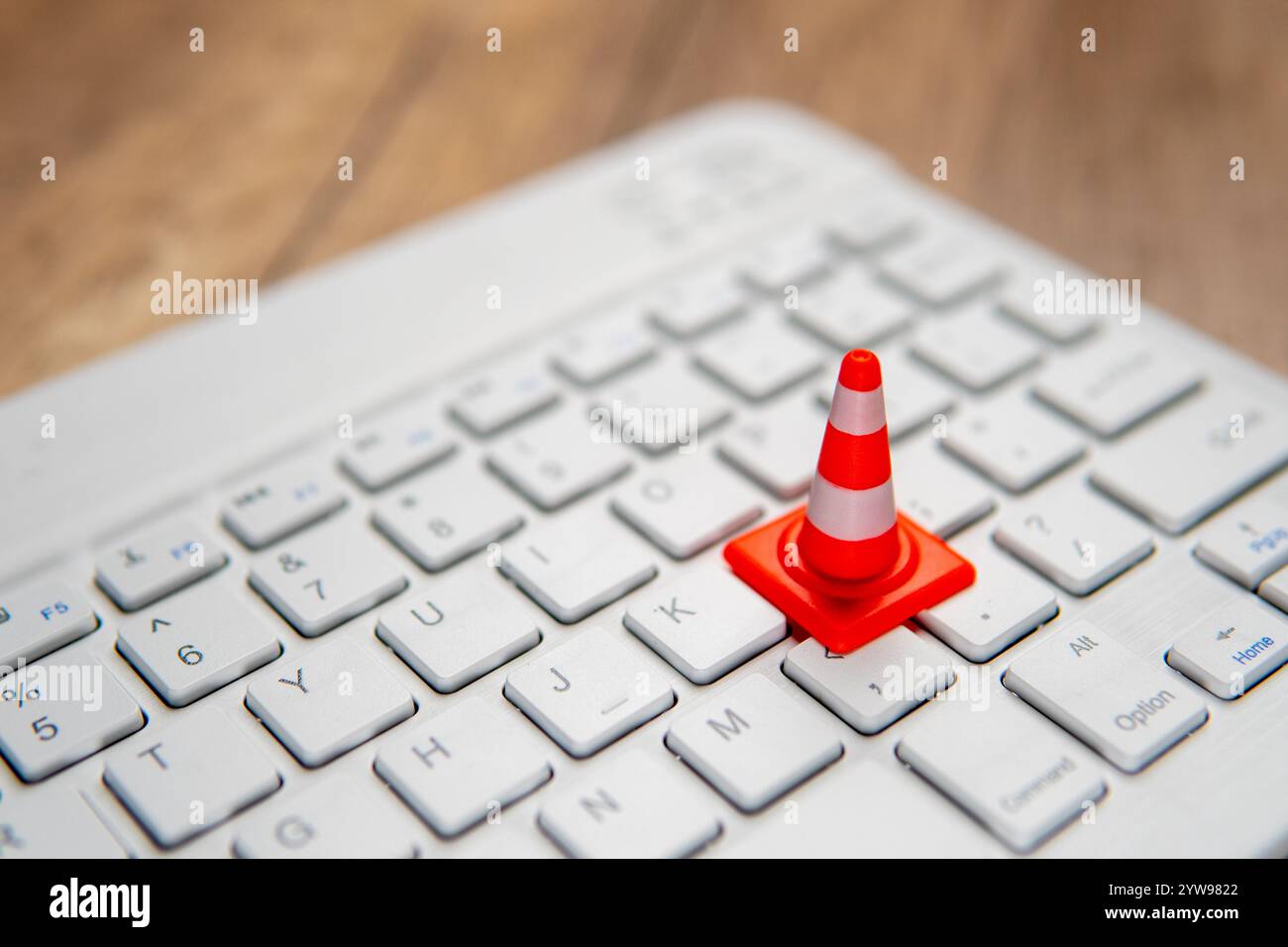 Ein Miniatur-Verkehrskegel auf einer Computertastatur. Website-Pflege, technische Schwierigkeiten, Website im Bau Konzept. Stockfoto