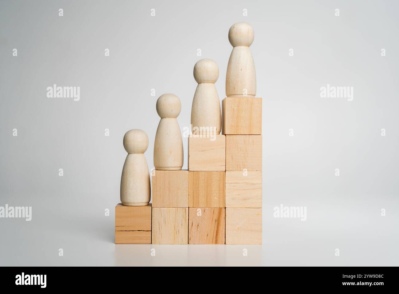 Rangfolge von Personen, Karrieretreppe und Zielerreichung Konzept. Verschiedenfarbige Volksfiguren als Arbeitgeber auf einer Treppe aus Holzwürfeln auf grauem Ba Stockfoto
